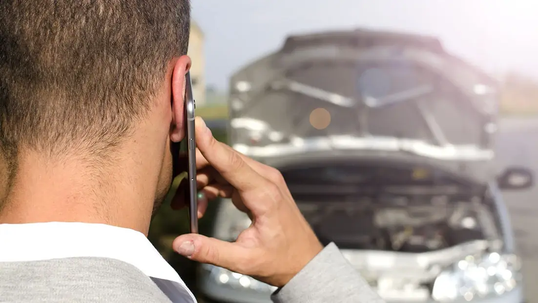 Specialist la telefon lângă o mașină cu capota deschisă